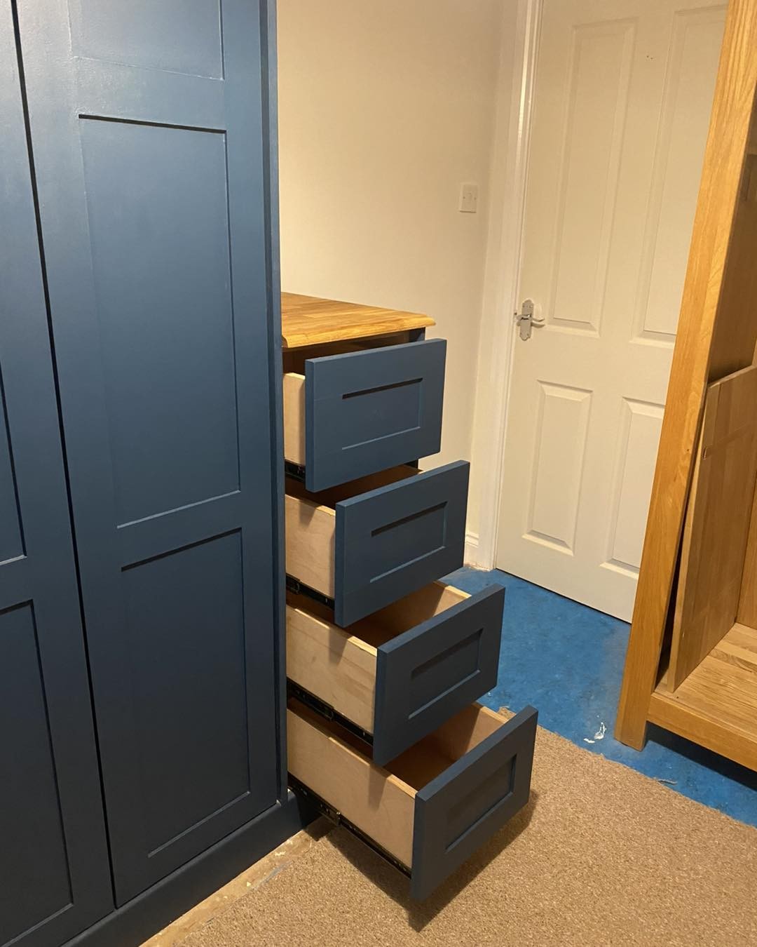 Push to open drawers pulled out from a navy built-in wardrobe