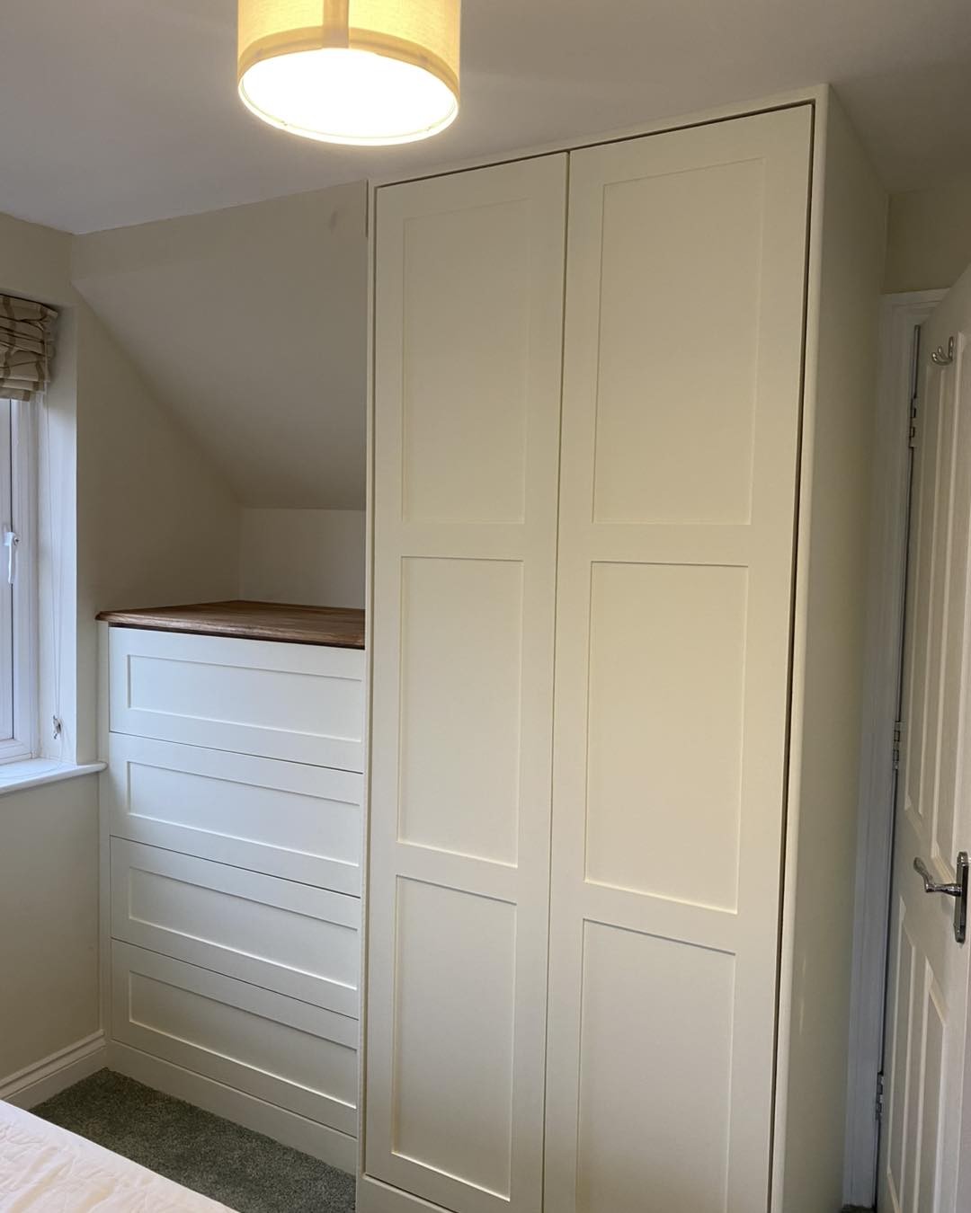 Painted built-in wardrobe with a drawer unit under a sloping ceiling